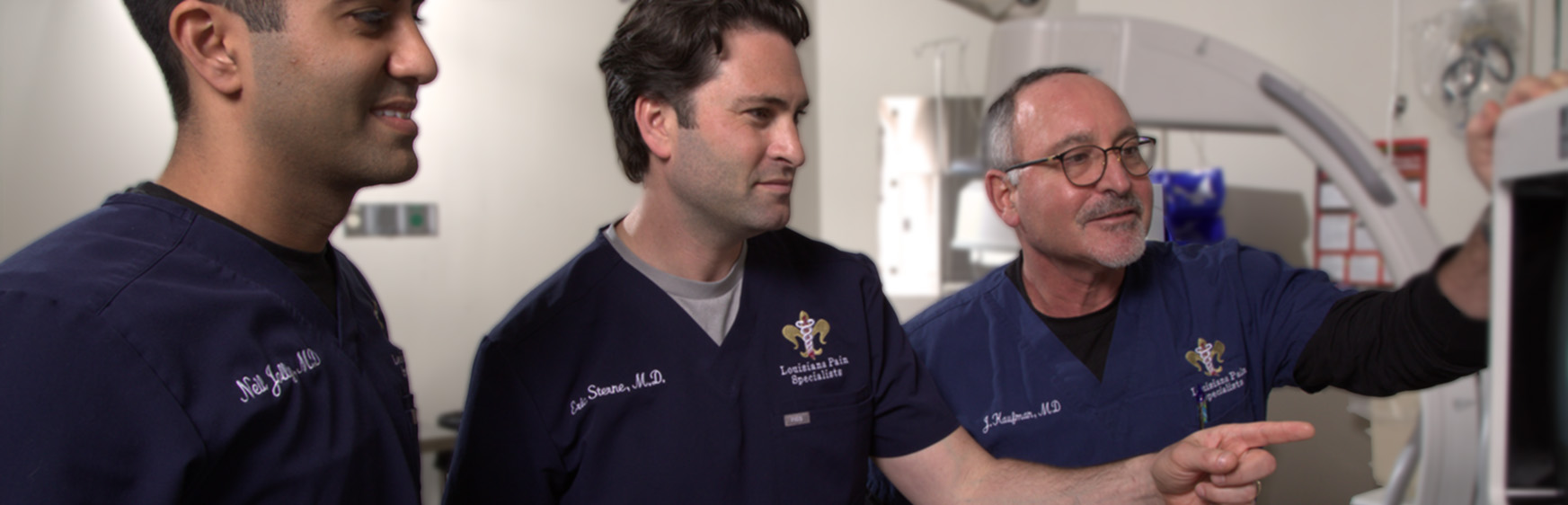 Drs. Jolly, Sterne, and Kaufman in the operating room, looking at a diagnostics screen.