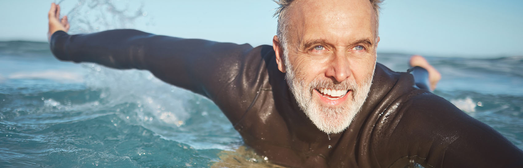 Pain-free senior citizen surfing in an ocean